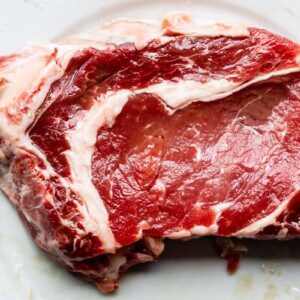 raw cut of ribeye steak, marbled with fat