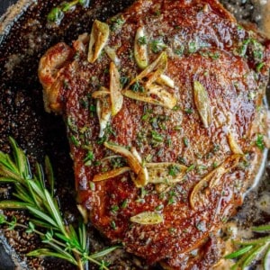 raw ribeye steak garnished with fresh herbs