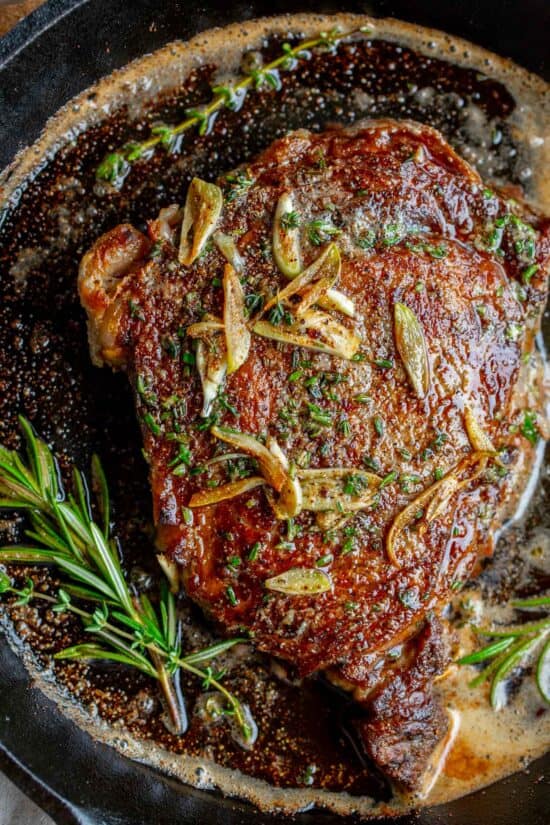 raw ribeye steak garnished with fresh herbs
