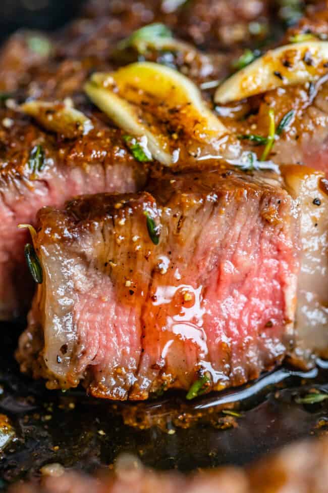 rib eye steak grilled or pan seared, close up of a medium rare slice leaking juices.