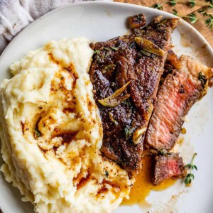 rib eye steak on plate in slices next to mashed potatoes