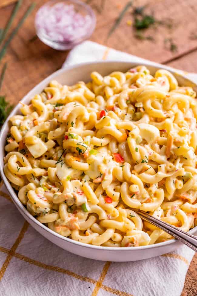 best macaroni salad ever in a bowl with a serving spoon on a white and gold tea towel. 