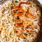 sliced pieces of cooked chicken in a pan of creamy pasta
