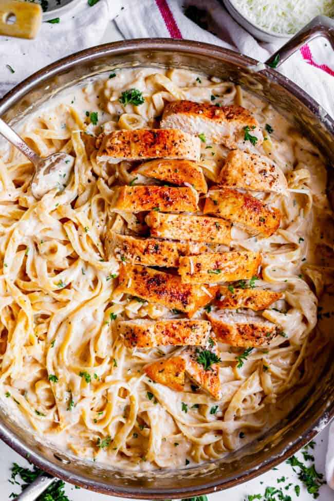 sliced pieces of cooked chicken in a pan of creamy pasta.