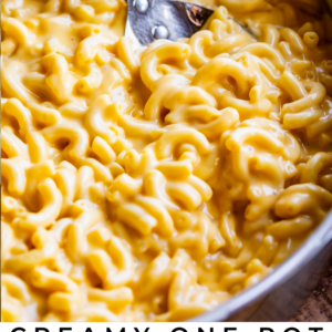 creamy stovetop mac and cheese in a metal pot with a spoon in it.