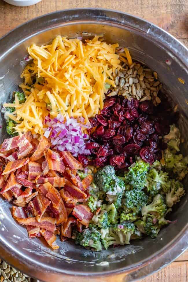 cheddar, sunflower seed, cranberry, broccoli, bacon, and red onion in a metal bowl