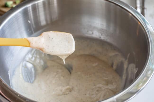 spoonful of dressing for bacon broccoli salad in a metal bowl