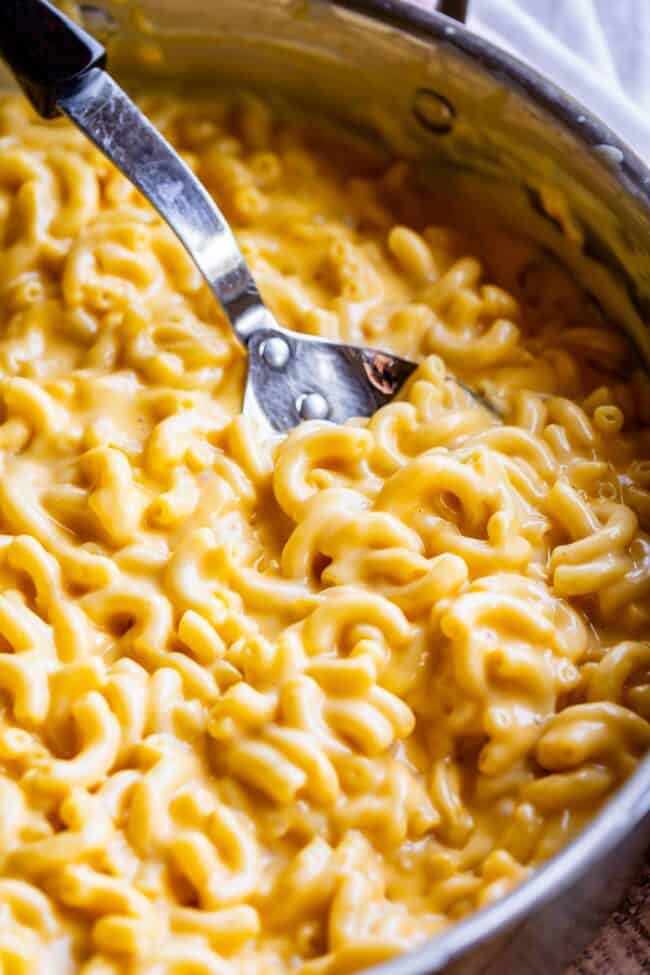 homemade mac and cheese in a pan with a large spoon.