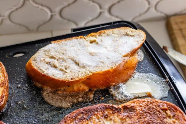 brioche french toast frying on an electric griddle, with sugar on top to caramelize.