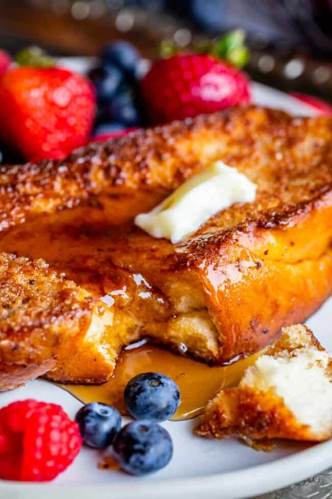 the best french toast, on a plate with berries, butter, and syrup.
