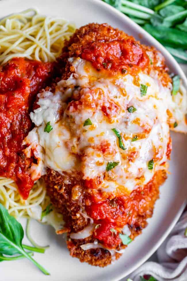 crispy parmesan chicken on a plate with pasta and marinara sauce