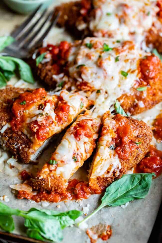 easy chicken parm, cut into strips with a fork in the background