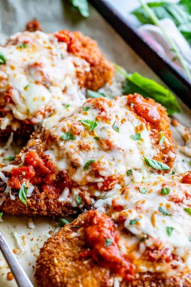 best chicken parmesan recipe, 3 cutlets lined up on a pan, shot from the side