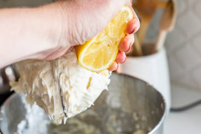 squeezing lemon juice into a stand mixer full of frosting