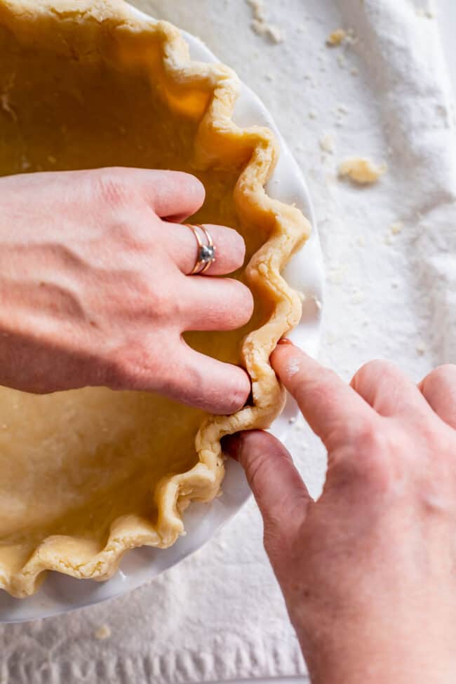 fluting the edges of pie crust to blind bake