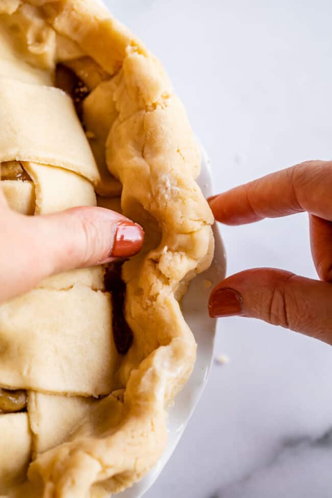 using fingers to flute a pie crust.
