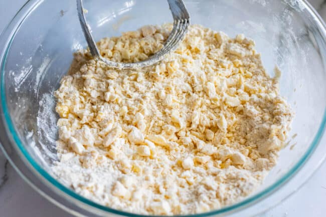 pea sized pieces of butter and shortening cut into flour in a bowl for pie crust.