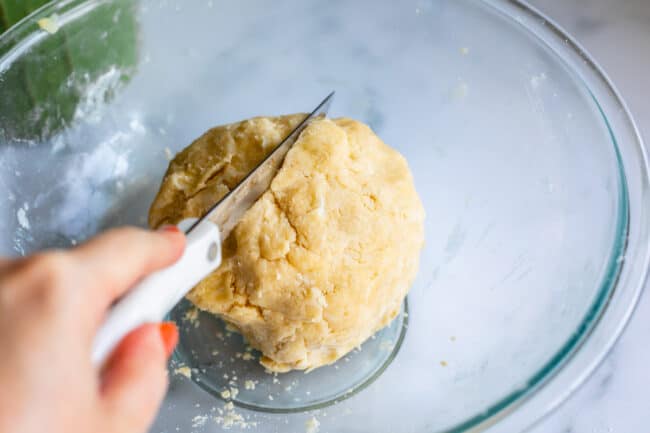 Cutting pie dough in half with a knife in a bowl