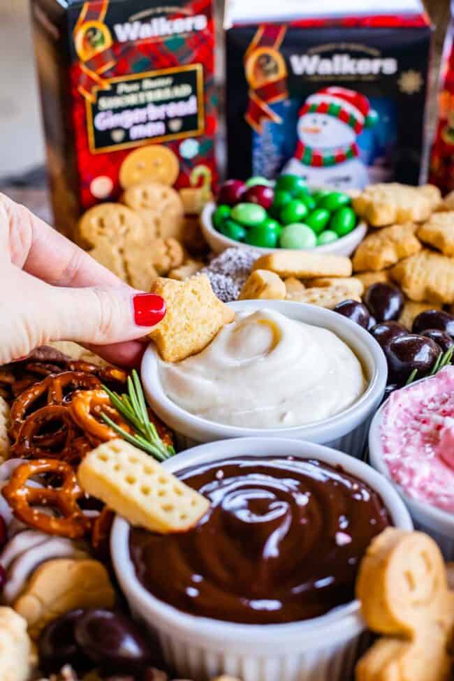 dipping shortbread into a marshmallow creme dip on a dessert charcuterie board 