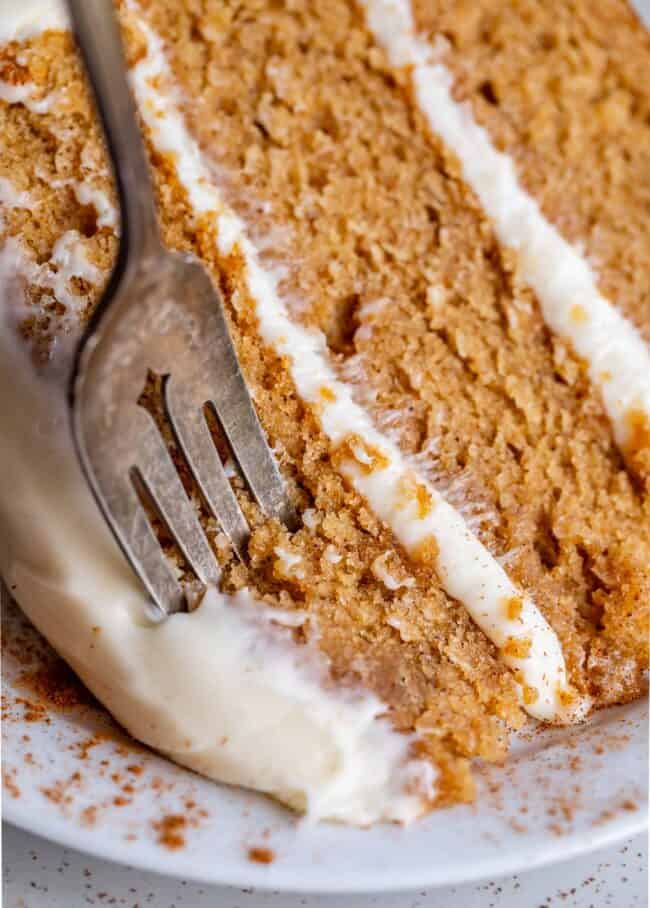 spice cake with cream cheese frosting on a plate with a fork in the cake.