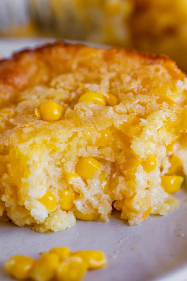creamed corn casserole on a plate with a bite taken out.