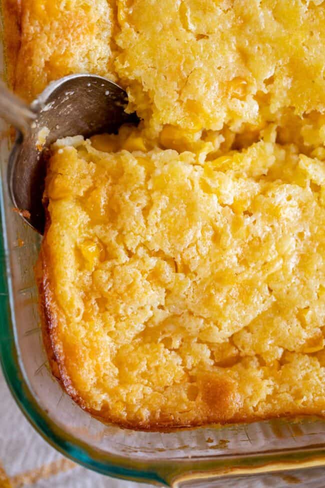 creamed corn casserole in a pan with a spoon.