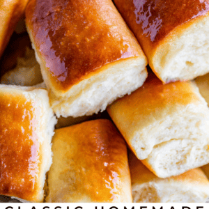 A close-up of golden-brown, fluffy Parker House rolls stacked on a plate, highlighting their soft texture. Text reads: Classic Parker House Rolls – So Soft & Fluffy! The Food Charlatan.
