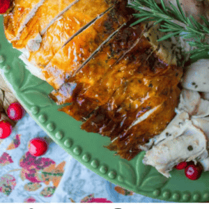 Close-up of sliced, golden-brown roasted turkey breast with sage butter, garnished with herbs on a green platter, cranberries on the side, and text reading Sage Butter Roasted Turkey, Perfect for the Holidays.