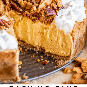 A close-up of a creamy pumpkin cheesecake in a graham cracker crust, topped with whipped cream and spiced pecan-graham crumble. A slice has been removed, revealing the smooth pumpkin filling inside.