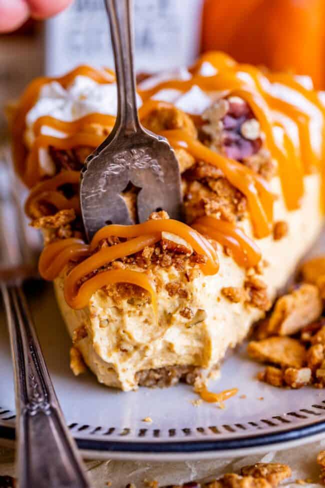 slice of easy no bake cheesecake drizzled with caramel, with a fork taking a piece.