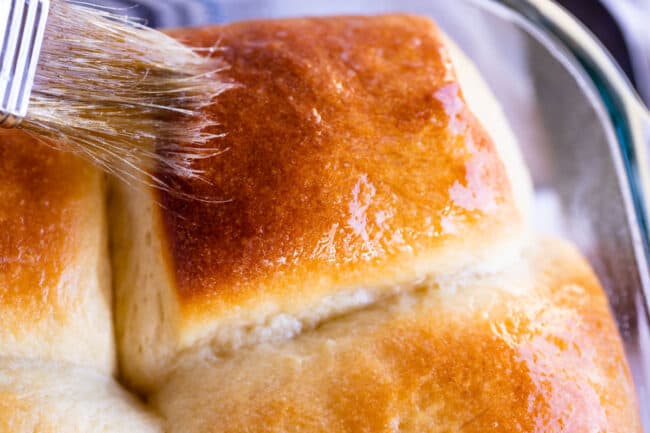 brushing butter on a golden dinner roll.