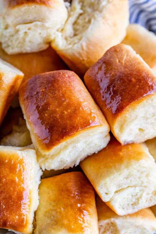 shiny buttery parker house rolls piled together in a bowl.