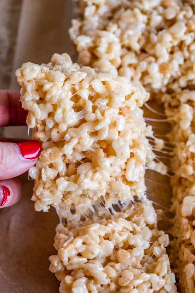 homemade rice Krispie Treats being pulled away from the pan with fingers.