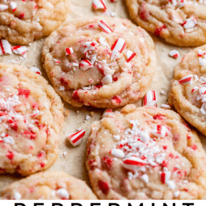 A tray of soft sugar cookies topped with crushed peppermint candy and surrounded by mini candy canes. The text reads: Peppermint Crunch Sugar Cookies with festive peppermint flavor - Perfect for the Holidays - The Food Charlatan.