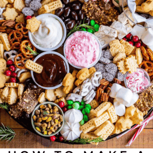 A dessert charcuterie board featuring cookies, pretzels, candies, meringues, nuts, and three types of indulgent sweet dips, all arranged in a circular pattern on a large tray.