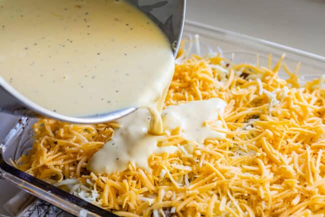 pouring egg mixture over a cheesy casserole.