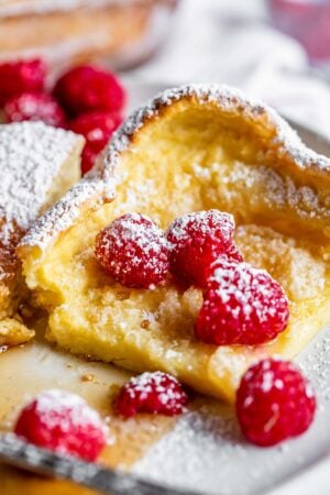 German pancake recipe with raspberries, syrup, and powdered sugar