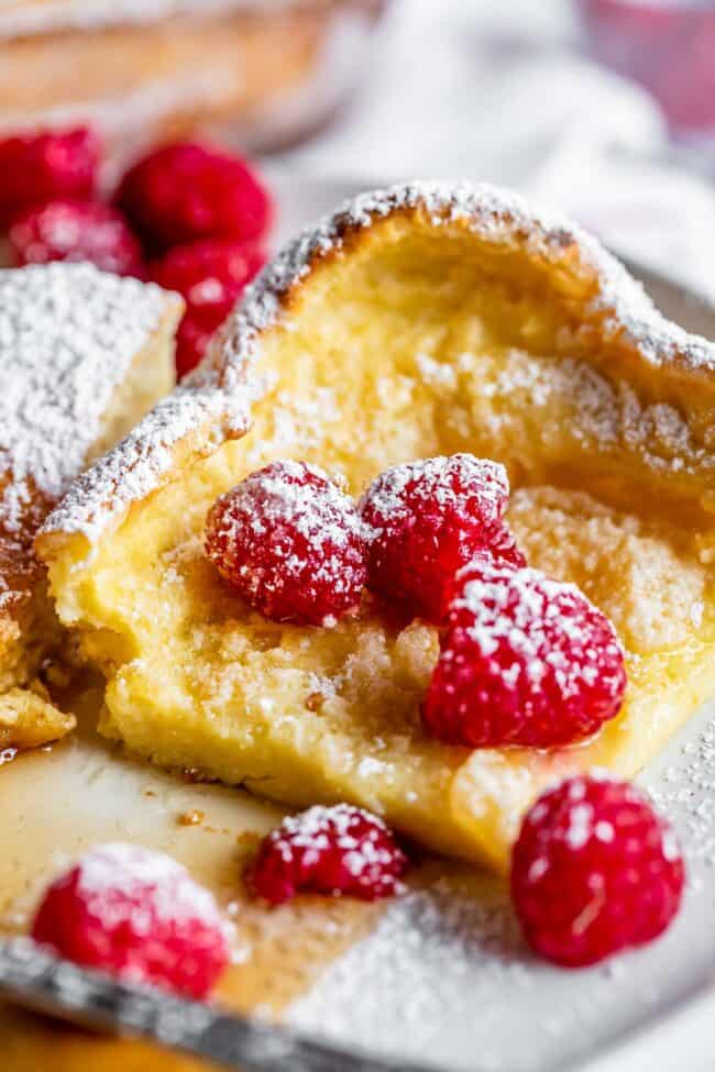 German pancakes with raspberries, syrup, and powdered sugar.