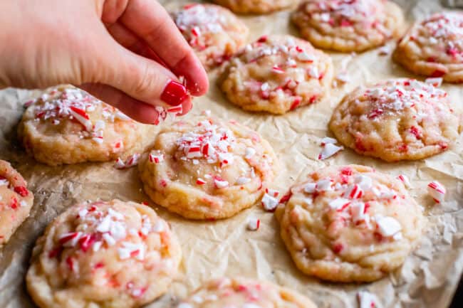 sprinkling crushed candy canes on top of sugar cookies