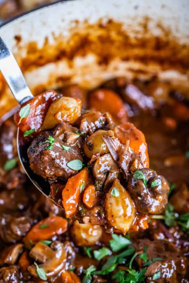 julia child beef bourguignon being lifted from the pot on a spoon