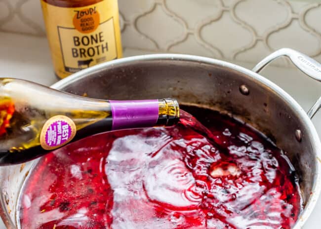 pouring pinot noir into a pan to be reduced for stew.