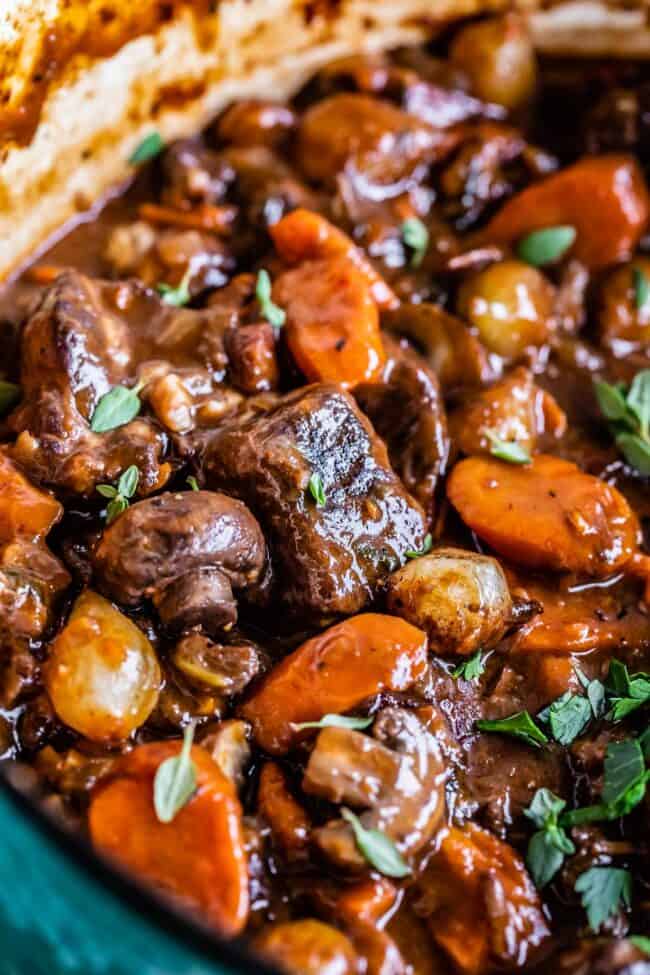 beef bourguignon with beef, mushrooms, carrots, pearl onions, in a teal pot.