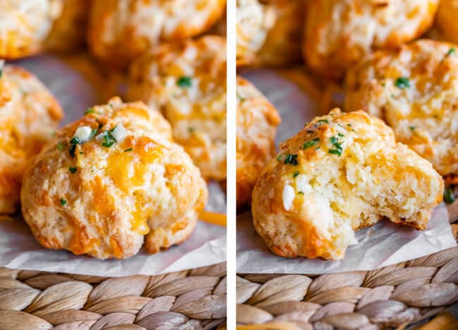 cheddar bay biscuits on parchment paper, one with a bite taken out.