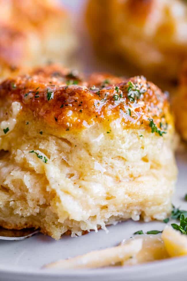 a tall, fluffy biscuit with cheddar cheese, butter, and fresh parsley.