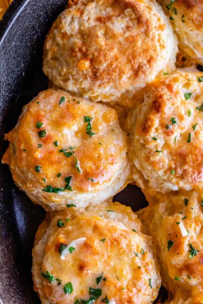 cheddar bay biscuits in a cast iron skillet brushed with garlic butter and parsley.