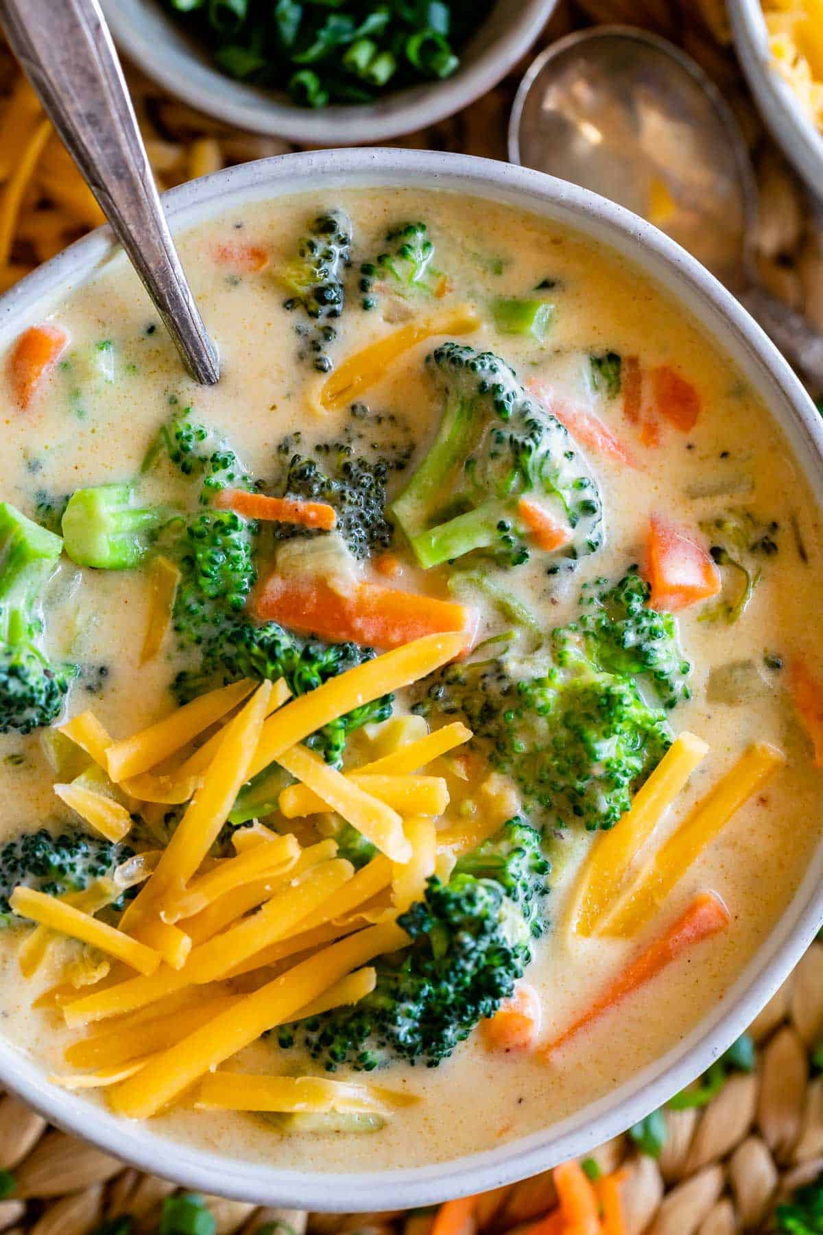 quick broccoli cheese soup in a white bowl with cheese on top and a silver spoon