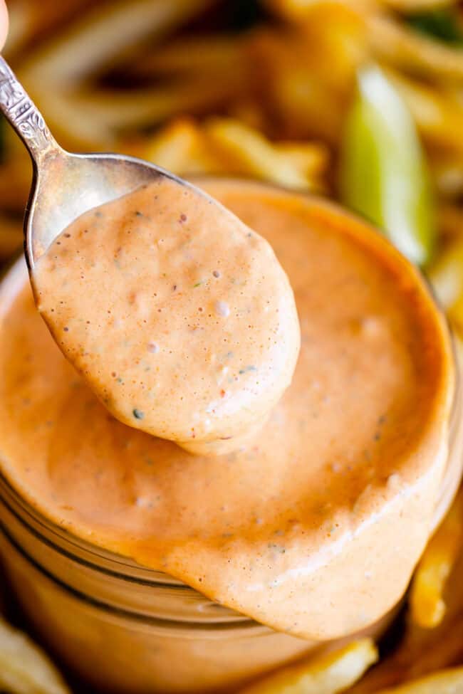 a spoon lifting homemade chipotle mayo from a jar.