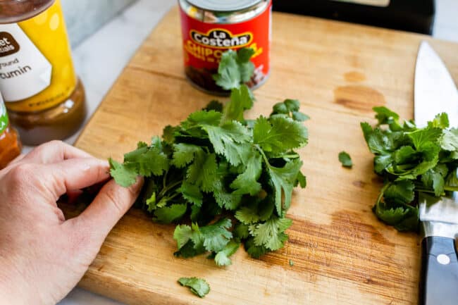 cilantro on a cutting board with a knife.