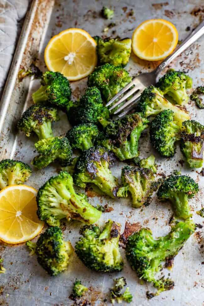 roasted broccoli recipe on a sheet pan with lemons and fork.