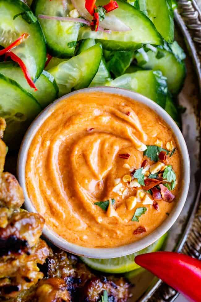 easy Thai peanut sauce in a bowl with cucumber salad and satay on the side.